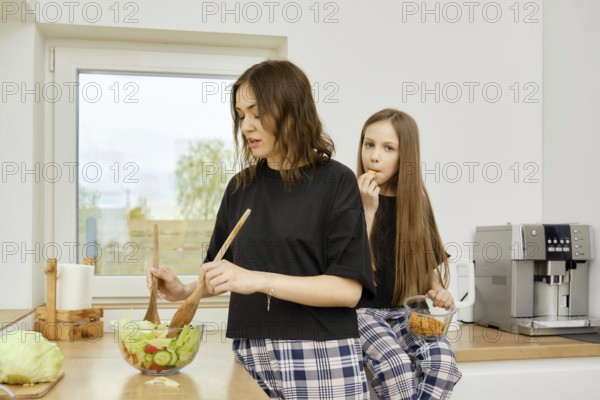 Mother preparing healthy food for her family. She is mixing fresh organic vegetables with sauce with wooden spoons.