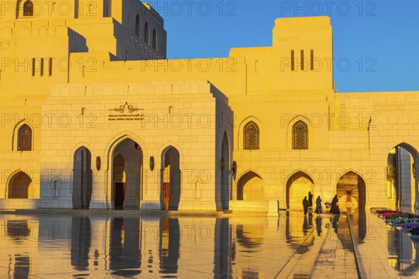 Local woman in traditional dress stroll across the main square of the Royal Opera in the evening light, Muscat, Arabian Peninsula, Sultanate of Oman