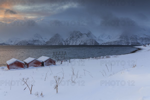 Red boat huts, coast, sea, waves, mountains, winter, snow, cloudy, windy, Lyngen Alps, Norway, Europe