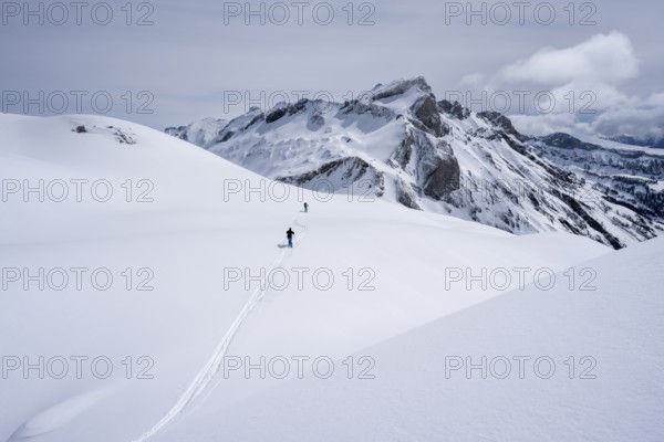 Two lonely ski tourers in a snow-covered mountain landscape, mountain peak Sex des Molettes in the background, Bernese Alps, Switzerland, Europe