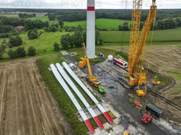 Dorsten, North Rhine-Westphalia, Germany, construction of a wind turbine, the first wind turbine of the Große Heide wind farm. A large mobile crane places the nacelle, the nacelle on the tower. The rotor blades, vanes and rotor hub are ready for assembly, Europe