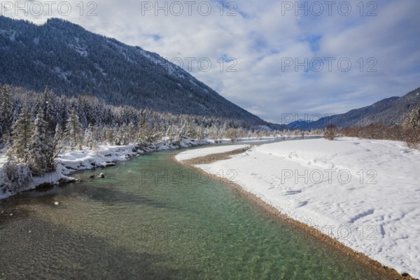 Isar valley in winter at temperatures of minus 18 degrees Celsius. Snow covered landscape with the Isar river flowing through. Some hoar frosted trees. Early morning at sunrise