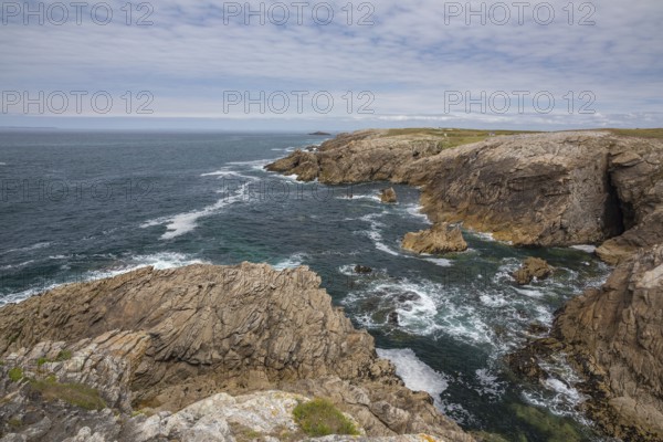 Rocky west coast of the Quiberon peninsula in Brittany, France, with a partly cloudy sky. Crashing waves and rocks, Europe