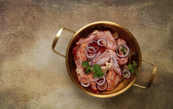 Chicken wings, in a brass saucepan, ready for cooking, grilling or baking, in a home kitchen, no people