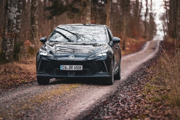 Black electric car driving on a forest path in autumn, e-car sharing vehicle from Deer Mobility, Gechingen, Black Forest, Germany, Europe