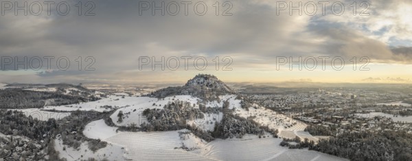Aerial view, panorama of the snow-covered Hegau volcano Hohentwiel with Germany's largest castle ruins at sunrise, in front of it Germany's highest vineyard, the Elisabethenberg at 505 metres above sea level, on the right the town of Singen, on the left on the horizon the neighbouring Hegau volcano Hohenkrähen, district of Constance, Baden-Württemberg, Germany, Europe