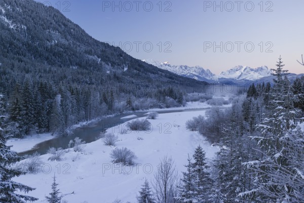 Isar valley in winter at temperatures of minus 18 degrees Celsius. Snow covered landscape with the Isar river flowing through. Some hoar frosted trees. Early morning