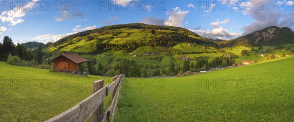 View along a wooden fence across a pasture to the mountains in the evening light, Dolomites, Odle Group, Sasso Putia Group, San Maddalena, Funes, Funes Valley, South Tyrol, Italy, Europe