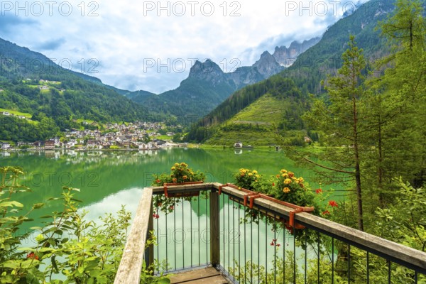 Wooden viewpoint overlooking the picturesque village of alleghe, reflecting on emerald waters framed by the majestic dolomites