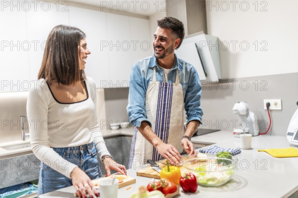 Young couple preparing healthy food together, having fun in modern kitchen, enjoying their time together