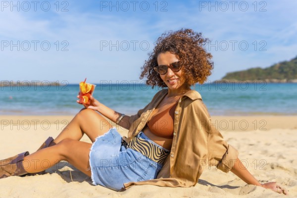 Portrait of a beauty sensual Arab woman eating fruit leaning on beach