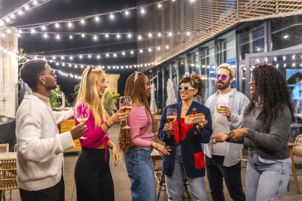 Woman celebrating birthday in the terrace of a night bar with multi-ethnic friends