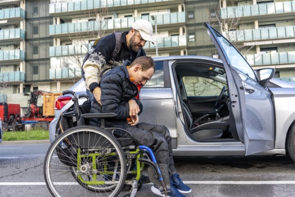 Caregiver assisting a disabled person getting into a car parked on a city street, showcasing support and accessibility for people with disabilities