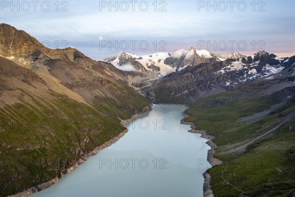 Picturesque mountain landscape at the summit Mont de la Blana at sunset with full moon, view of blue mountain lake, reservoir Lac des Dix and summit Mont Blanc de Cheilon with glacier, Hérémence, Valais, Western Alps, Switzerland, Europe