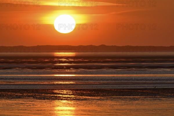 Sunset over the North Sea at low tide, the outline of the island of Juist on the horizon, Norddeich, Lower Saxony, Germany, Europe