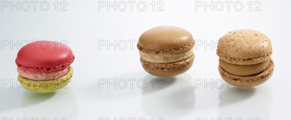 Three differently coloured macarons in front of a white background, studio shot