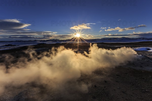 Hot springs and geothermal area in front of mountain landscape in winter, sunbeams, cloudy mood, Hverir, Namafjall, Myvatn, Iceland, Europe