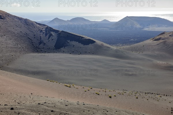 Volcanic landscape on the Canary Island of Lanzarote in Timanfaya National Park, Lnzarote, in the background on the Atlantic Ocean horizon, Canary Islands, Spain, Europe