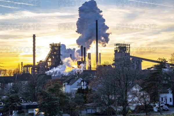 Blast furnace Schwelgern 1, Black Giant, Schwelgern 2 ThyssenKrupp Steel plant Schwelgern in Duisburg-Marxloh is part of the Bruckhausen steelworks, residential buildings in the Marxloh district, extinguishing cloud from the Schwelgern coking plant, sunset, North Rhine-Westphalia, Germany, Europe