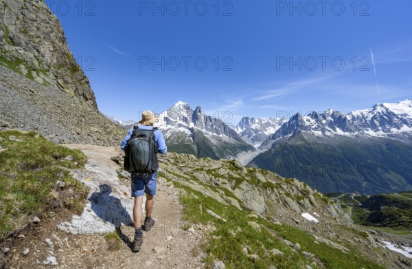 Mountaineer on a hiking trail in front of a mountain landscape, view of the mountain peaks Aiguille Verte and Grandes Jorasses of the Mont Blanc massif, Aiguilles Rouges, Chamonix-Mont-Blanc, Haute-Savoie, France, Europe