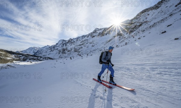 Ski tourers in the rear Martell Valley, snow-covered mountain landscape with sun star, Ortler Alps, Vinschgau Valley, Italy, Europe