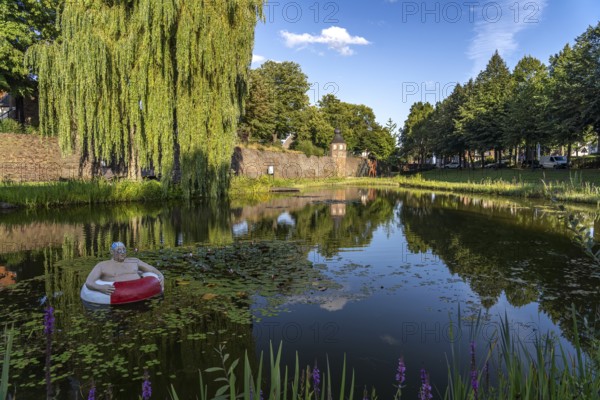 Frog pond with sculpture of Paul, the floating tyre man and the town wall with guard tower in Rees, Lower Rhine, North Rhine-Westphalia, Germany, Europe