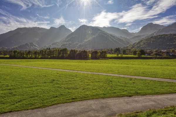 Sunny mountain landscape with green meadows and trees in front of a picturesque Alpine panorama under a clear sky, Klobenstein