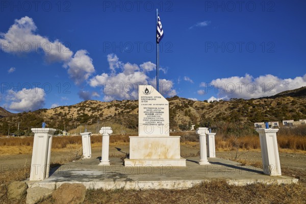 Greek monument with flag under clear blue sky and mountainous background landscape, Christopher Litos Monument, Pigadia, town and harbour, Pigadia Bay, main town, Karpathos, Dodecanese, Greek Islands, Greece, Europe