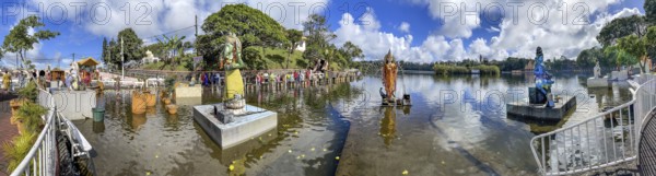 Panorama panoramic photo of Hinduism pilgrimage site Saint Hindu Lake Ganga Talao for Hindi devotees of Hindu religion, from left elephant god Ganesha, goddess Parvati deity Lord Shiva standing on pedestal in Saint Lake Ganga Talao, crater lake Grand Bassin, Le Petrín, Mauritius, Africa