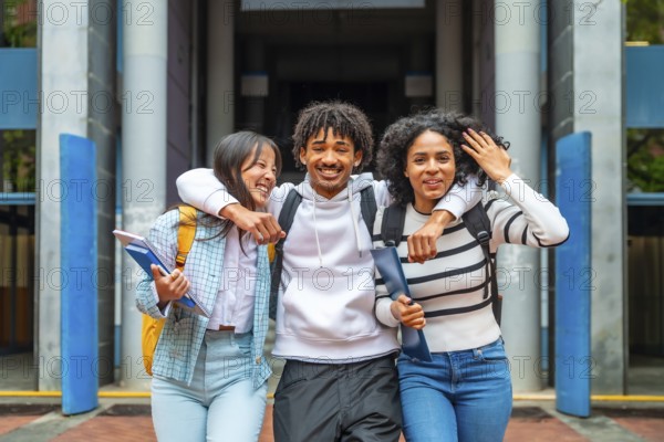 Portrait of three multi-ethnic friends in the university embracing together smiling at camera with happy look