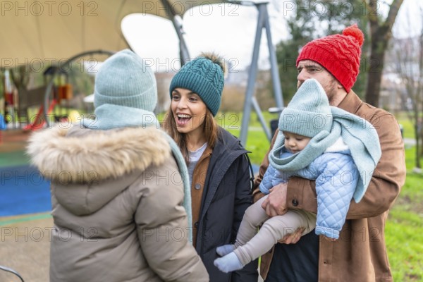 Parents and children enjoying playful moments together in winter attire at the playground, sharing laughter and creating joyful memories