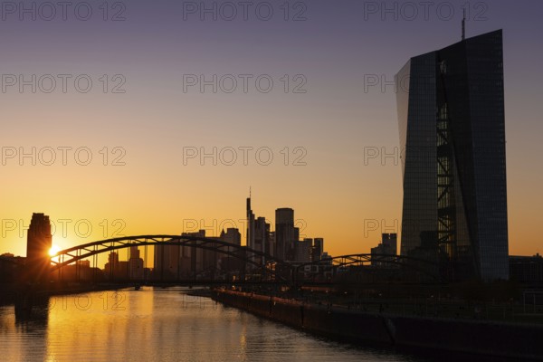 The sun sets behind the European Central Bank (ECB) and the Frankfurt skyline, Osthafen, Frankfurt am Main, Hesse, Germany, Europe