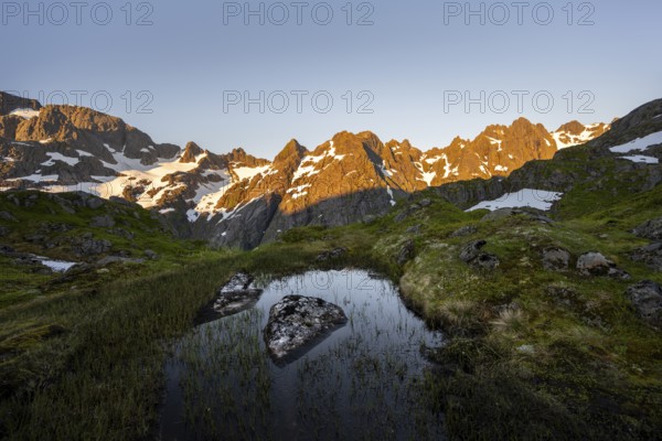 Rocky mountain peaks with reflection, small pond in moor landscape at Trollfjord Hytta, mountain landscape with alpenglow at sunrise, at Trollfjord, Lofoten and Vesterålen, Nordland, Norway, Europe