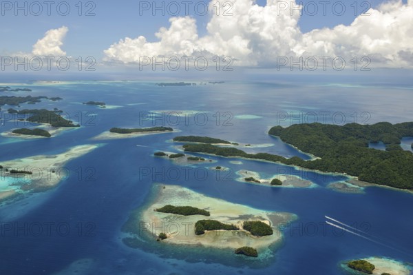 Aerial view bird's eye view of UNESCO cultural heritage natural heritage Rock Islands islands in southern lagoon of island paradise island state Palau in the Pacific West Pacific, on the horizon white clouds cumulus in blue sky, Republic of Palau, Micronesia, Australia, Oceania