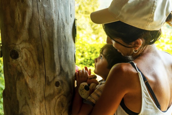 Mother and son smelling a tree in a sensory park to enjoy nature and the senses, Black Forest, Germany, Europe