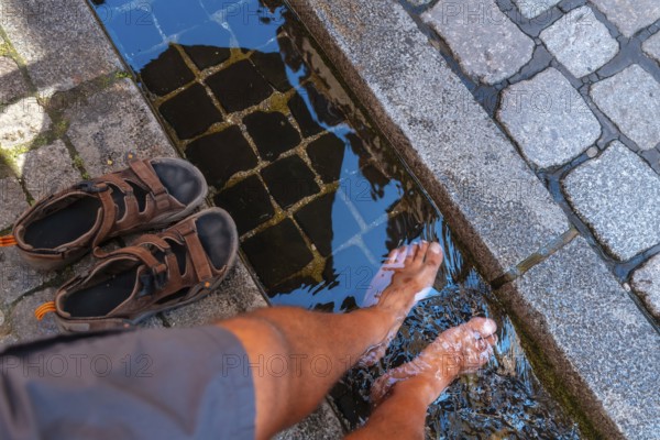 A man cooling his feet in the water canals of Freiburg im Breisgau, Germany, Europe