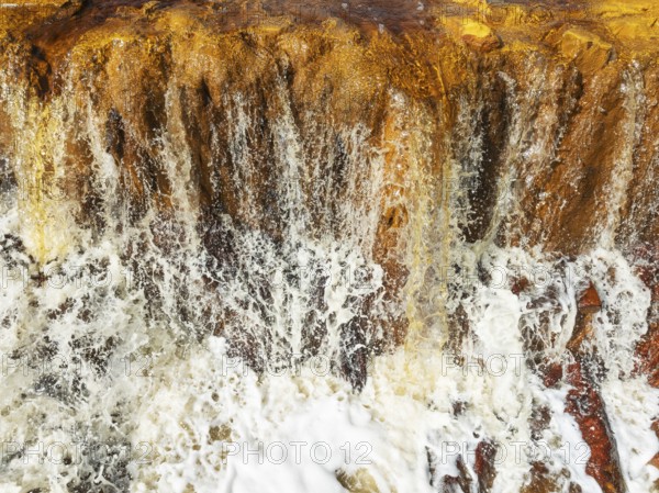 Detail of a waterfall in the Rio Tinto (Red river) with its orange-red hue due to oxidised iron minerals. Aerial view. Drone shot. Huelva province, Andalusia, Spain, Europe