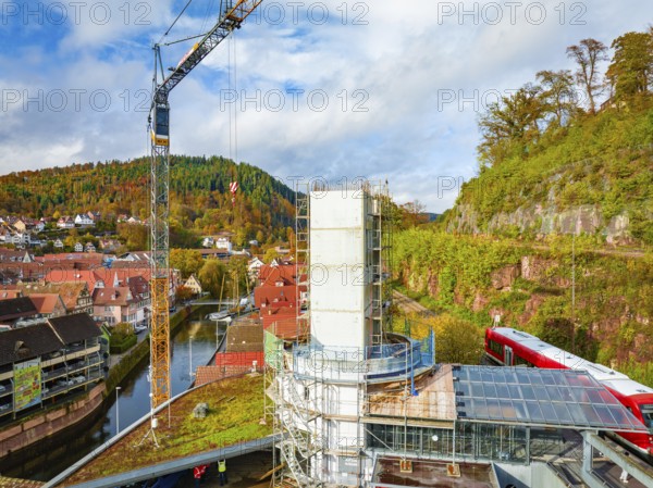 Building under construction with crane, surrounded by a picturesque autumn landscape and a river, ZOB Calw conversion for Hermann Hessebahn, Calw, Black Forest, Germany, Europe