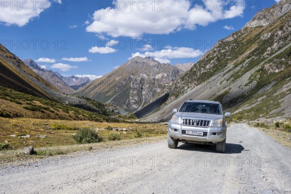 Off-road vehicle on a gravel track, picturesque mountain valley, mountain landscape with white mountain peaks, Tian Shan Mountains, Issyk-Kul, Kyrgyzstan, Asia