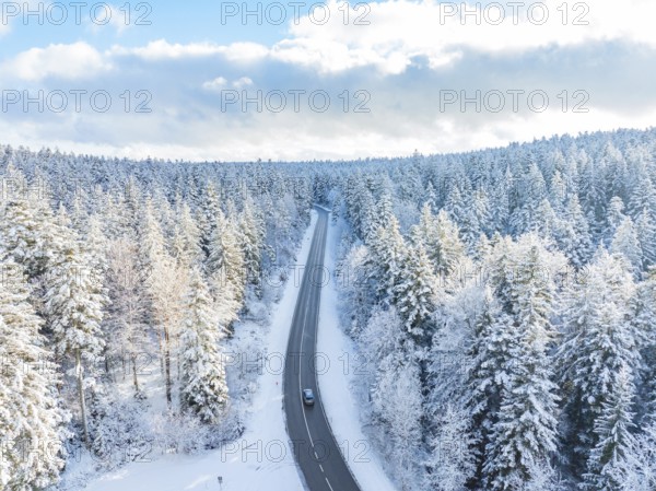 A road winds through a snowy winter forest under a blue sky, Bad Wildbad, district of Calw, Black Forest, Germany, Europe