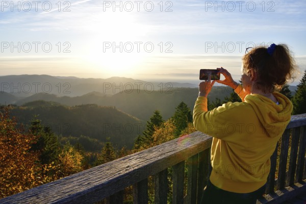 Woman photographing the sunset at Schliffkopf, near Baiersbronn, Freudenstadt district, Black Forest, Baden-Württemberg, Germany, Europe