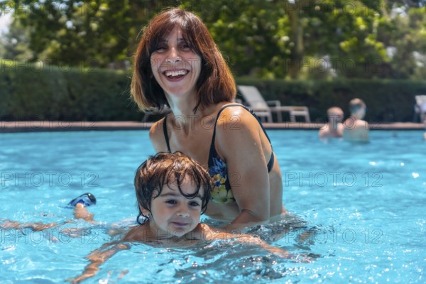 Mother and son in the pool on summer vacation, learning to swim with his mother