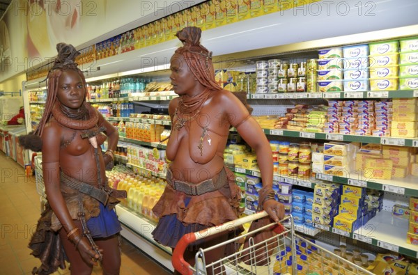 Traditionally dressed Himba women standing in front of the refrigerated section of a supermarket, Opuwo, Kaokoland, Kunene, Namibia, Africa