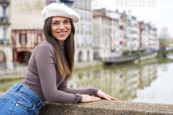 Stylish beauty woman smiling at camera while leaning in a rail visiting the river of a city