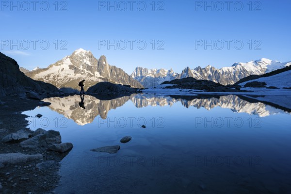 Mountaineer, silhouette in front of mountain landscape in the evening light, water reflection in Lac Blanc, mountain peak, Aiguille Verte, Grandes Jorasses, Aiguille du Moine, Mont Blanc, Mont Blanc massif, Chamonix-Mont-Blanc, Haute-Savoie, France, Europe