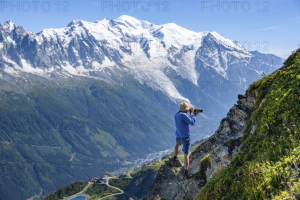 Photographer with zoom lens in mountain landscape, in front of glaciated mountain peak of Mont Blanc, Mont Blanc massif, Chamonix-Mont-Blanc, Haute-Savoie, France, Europe