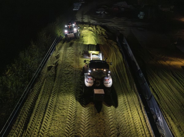 Two tractors filling and levelling a silo at night, maize harvest, Dachtel, Black Forest, Germany, Europe