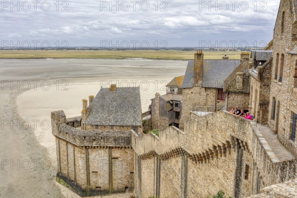 Sweeping views from Mont Saint-Michel over historic buildings to the sea under a cloudy sky, Le Mont-Saint-Michel