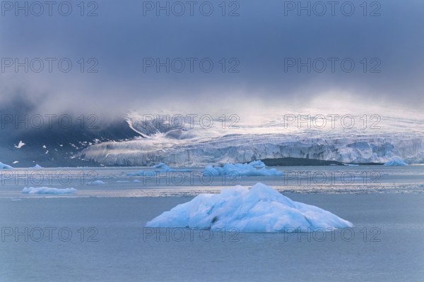 Iceberg floating in the sea outside a glacier in the Arctic with beautiful light and low clouds, Svalbard, Norway, Europe