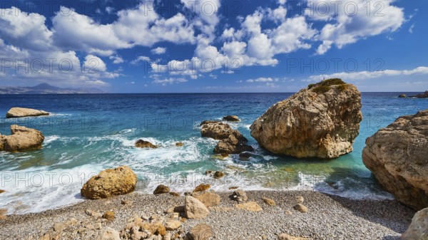Stony beach with large rocks and gentle waves under a blue sky, Kato Lakkos Beach, still almost unspoilt bay, not accessible by car, Kato Lakkos, east coast, Karpathos, Dodecanese, Greek Islands, Greece, Europe